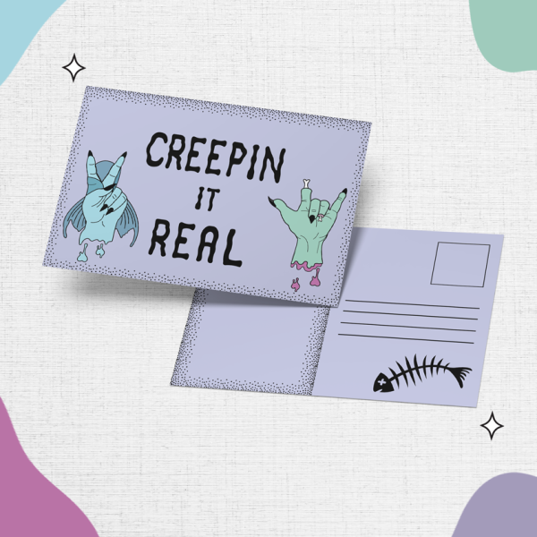 The "Creepin it Real Postcard features two cartoon characters: a mermaid hand making the 'rock n roll' hand sign and a green hand making a rock sign, with the text "Creepin it real" displayed above them. The back offers space for writing alongside an image of a fish skeleton, all surrounded by colorful abstract shapes.