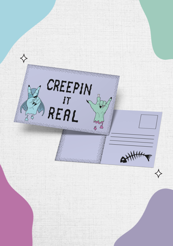 The "Creepin it Real Postcard features two cartoon characters: a mermaid hand making the 'rock n roll' hand sign and a green hand making a rock sign, with the text "Creepin it real" displayed above them. The back offers space for writing alongside an image of a fish skeleton, all surrounded by colorful abstract shapes.