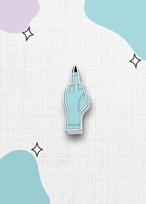 A turquoise, stitched cartoon hand sticker, with an extended middle finger, set against a white textured background. The hand is surrounded by abstract blobs of pastel colors and small star-shaped accents.