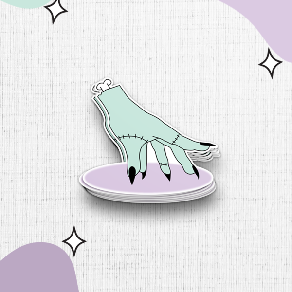 Illustration of a dismembered, stitched-together hand in a pale green hue with black nails, resting palm-down on a lavender oval. The background is white with textured patterns and abstract shapes in green and purple, complemented by small star-like sparkles.